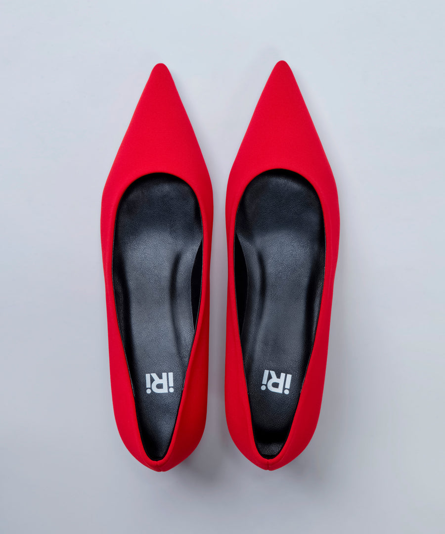 Pair of red high-heeled shoes with 'IRI' branding on a light gray background