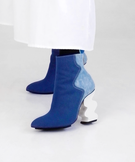 Model wearing and walking casually while wearing INES Blue Denim Ankle Boots, styled with knee-length white wide skirt